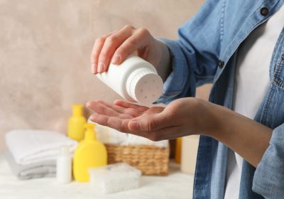 Mom applying talc powder from plastic tube. Baby hygiene