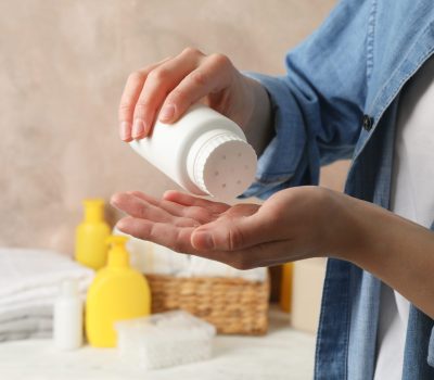 Mom applying talc powder from plastic tube. Baby hygiene